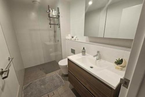 a white bathroom with a sink and a toilet at Tucked Away on the Tenth Floor at Woden in Phillip