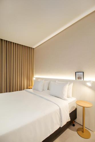 a bedroom with a large white bed and a table at Intercity Florianopolis in Florianópolis