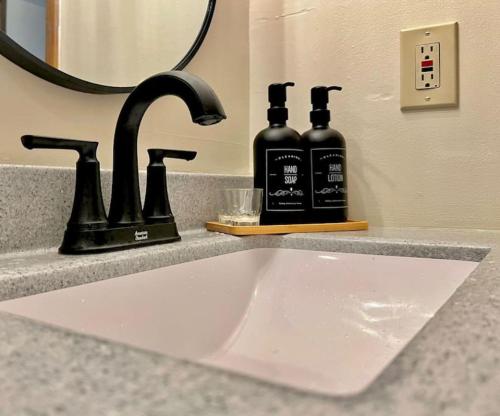 a bathroom sink with two black bottles on a counter at Quiet Cozy 2BR APT Black out Curtains in Peoria