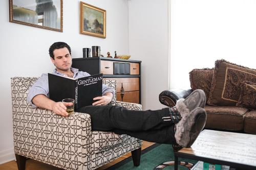 a man sitting in a chair reading a book at Cellar House NOTL - Entire Home in the Heart of Niagara-on-the-Lake in Niagara on the Lake