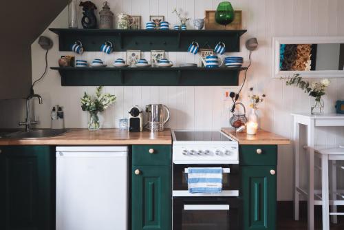 een keuken met groene kasten en een witte kachel bij Fourteen Providence Place, Calstock, Cornwall, self catering cottage in Calstock