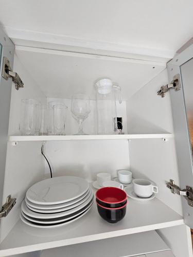 a white cabinet with plates and bowls and glasses at L207 Apartamento em resort à beira lago in Brasilia