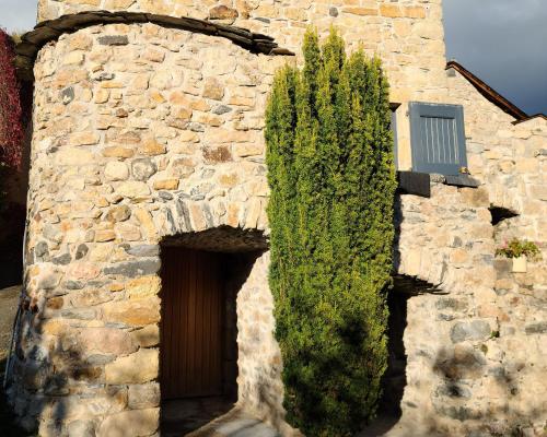 - un bâtiment en pierre avec une porte et une brousse à côté dans l'établissement Les Gîtes de la Jonte, à Gatuzières