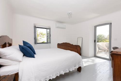 a white bedroom with a large bed with blue pillows at Villa Floresco in Nerezine