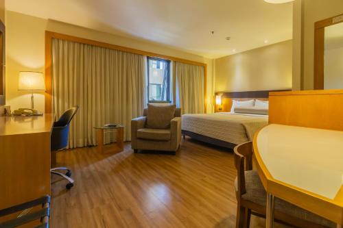 um quarto de hotel com uma cama e uma cadeira em Flat Executive Transamerica Faria Lima Itaim em São Paulo