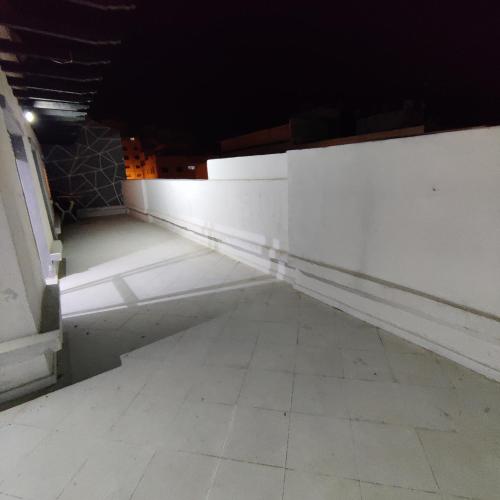 Habitación oscura con paredes blancas y suelo de baldosa. en boughaz appartement Terrasse, en Hajreien