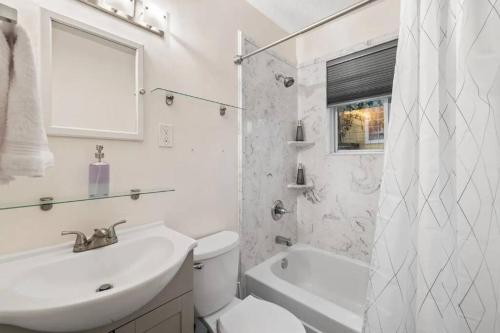 La salle de bains blanche est pourvue d'un lavabo, de toilettes et d'une douche. dans l'établissement Glamorous @Midtown W/ King suite, à Memphis