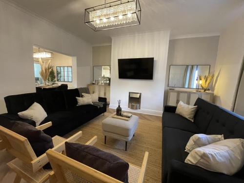 a living room with black couches and a tv at Château by the Sea - Hotel style 3 bed optional hot tub in Newbiggin-by-the-Sea