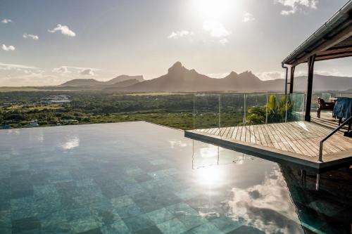 a house with a swimming pool with mountains in the background at Villa Teranga avec vue panoramique sur la baie de Tamarin in Tamarin