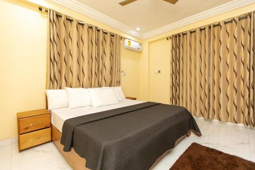 a bedroom with a bed and a window with curtains at Washington Apartments - just 25mins drive from the Airport in Kwashieman