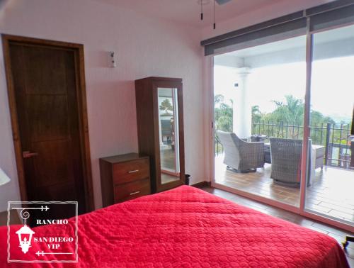 a bedroom with a red bed and a balcony at Rancho San Diego, Villa llena de Vida VIP in Ixtapan de la Sal