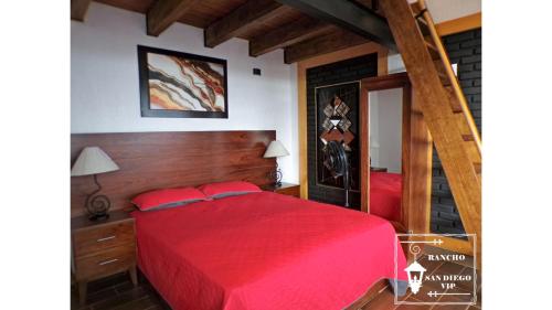 Un dormitorio con una cama roja y una escalera en Rancho San Diego, Villa llena de Vida VIP, en Ixtapan de la Sal