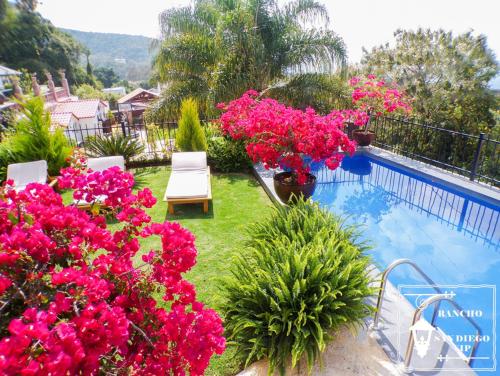 un balcón con flores rosas y una piscina en Rancho San Diego, Villa llena de Vida VIP, en Ixtapan de la Sal