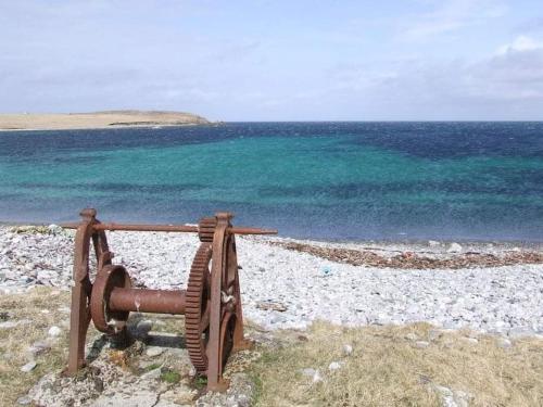 a rusty object on a beach near the ocean at Squealing Pig Bothy in Bragor