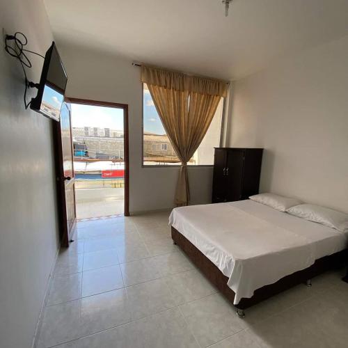 a bedroom with a bed and a large window at Hotel La Mansión del Sol in Tuluá