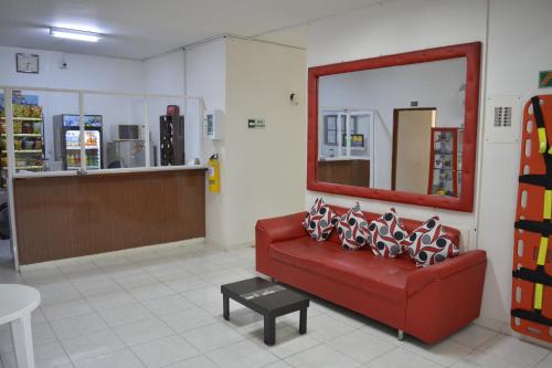 a waiting room with a red couch and a mirror at Hotel La Mansión del Sol in Tuluá