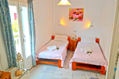 two beds in a room with a window at Sanoudos in Naxos Chora