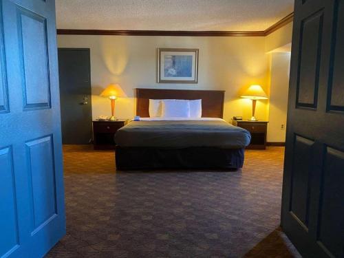Dominion Inn and Suites في ساندستون: غرفه فندقيه بسرير ومصباحين