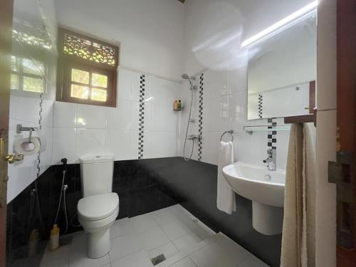 a white bathroom with a toilet and a sink at Caro Villa in Induruwa