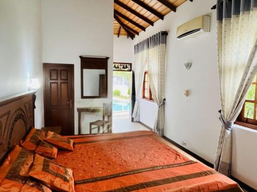 a bedroom with a bed with an orange blanket on it at Caro Villa in Induruwa