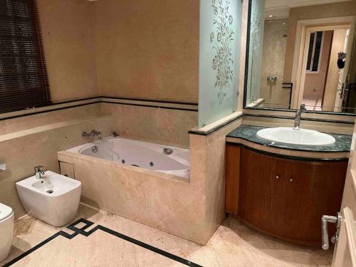 a bathroom with a tub and a sink and a toilet at Suite présidentielle avec jacuzzi in Rabat