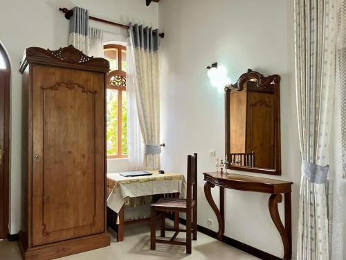 a room with a wooden cabinet and a table and a mirror at Caro Villa in Induruwa