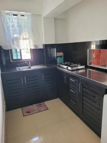 cocina con armarios negros, fregadero y ventana en Holiday Home, en Lautoka