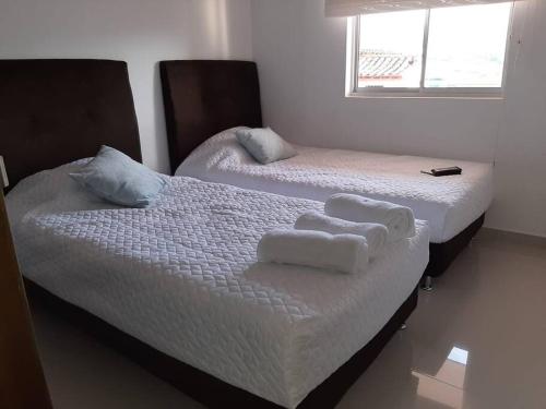 2 letti in una camera da letto con asciugamani di Apartamento amplio con piscina, hermosa vista a la ciudad de San Gil a San Gil