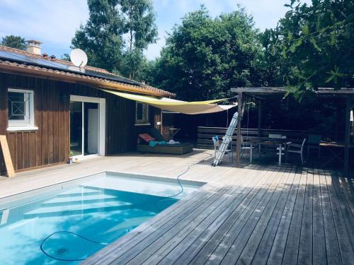 une terrasse avec une piscine, une table et un parasol jaune dans l'établissement comme chez vous, à Taussat-les-Bains