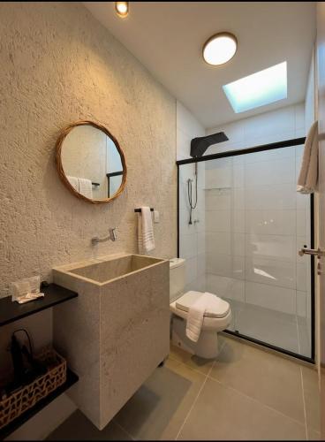 a bathroom with a sink and a toilet and a mirror at Villa Sapê 9 in São Miguel dos Milagres