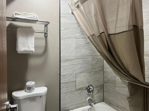 two pictures of a bathroom with a toilet and a shower at Studio 6 Ogden, UT 21st Street in Ogden