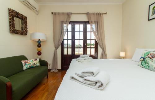 ein Schlafzimmer mit einem weißen Bett und einem grünen Sofa in der Unterkunft Villa a Sul in Albufeira