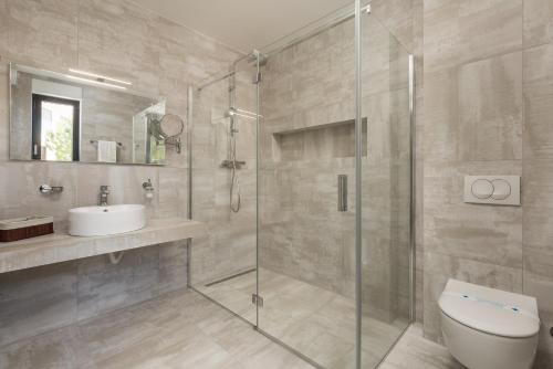 a bathroom with a shower and a toilet and a sink at HADRIE LUXURY RESORT AND VILLAS ROVA ed in Vantačići