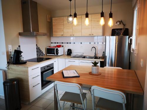 cocina con mesa de madera con sillas y nevera en Au Cocon d'Ornon - Top Location Bordeaux, en Villenave-dʼOrnon