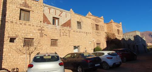 two cars parked in front of a brick building at Tizi Maison d'Hôtes in Telouet