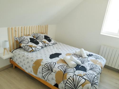 ein kleines Schlafzimmer mit einem Bett mit einer Bettdecke und Kissen in der Unterkunft Plume - Dormir Comme A La Maison in Guérande