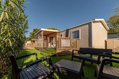 a home with two benches and a house at Mobil Home Luxe 3 chambres climatisé Canet en Roussillon in Canet-en-Roussillon
