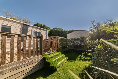 a garden with a wooden deck and a patio at Mobil Home Luxe 3 chambres climatisé Canet en Roussillon in Canet-en-Roussillon