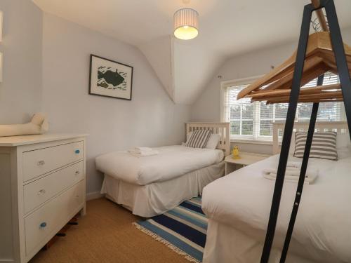 a bedroom with two beds and a dresser and a window at 6 The Whinlands in Leiston