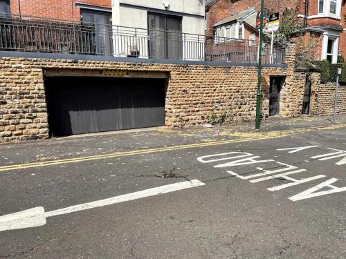 an empty street with a brick building with a garage at Lovely two bed flat with free parking (4 117) in Nottingham
