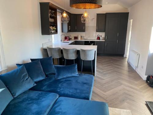 a living room with a blue couch and a kitchen at Stanley Place in Greystones