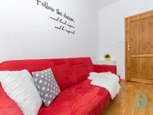 a red couch in a living room with a quote on the wall at Dream Room in Gdańsk