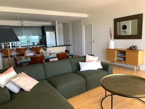 uma sala de estar com um sofá verde e uma mesa em Location, location, location! em Napier