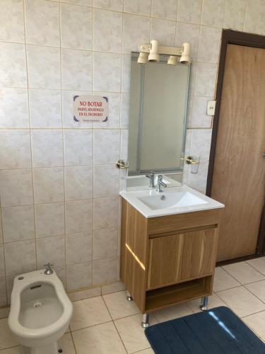 a bathroom with a toilet and a sink and a mirror at Hostal Argentina Osorno in Osorno