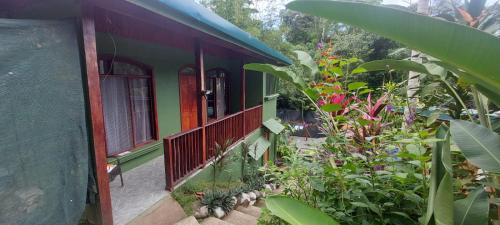ein grünes Haus mit einem Balkon mit Blumen und Pflanzen in der Unterkunft Corcovado & Drake Inn in Drake