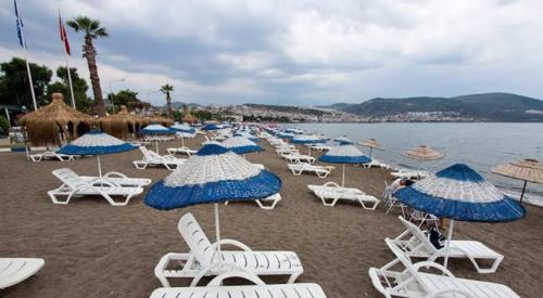 een stel stoelen en parasols op een strand bij Beach Village in Dikili