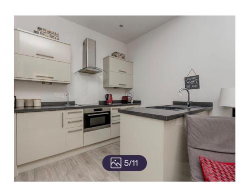 uma cozinha com armários brancos e uma bancada em King’s stable 2 rooms em Edinburgo