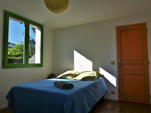 une chambre avec un lit bleu et une fenêtre dans l'établissement Izpi Urdin Holistic surfhouse, à Saint-Jean-de-Luz
