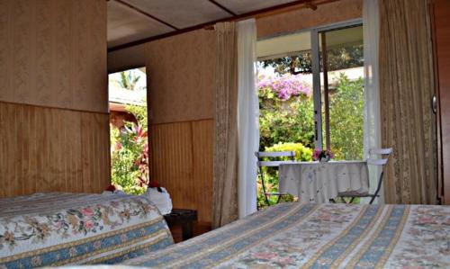 a bedroom with two beds and a large window at Hare o Koro (Ex Vai Kapua) in Hanga Roa