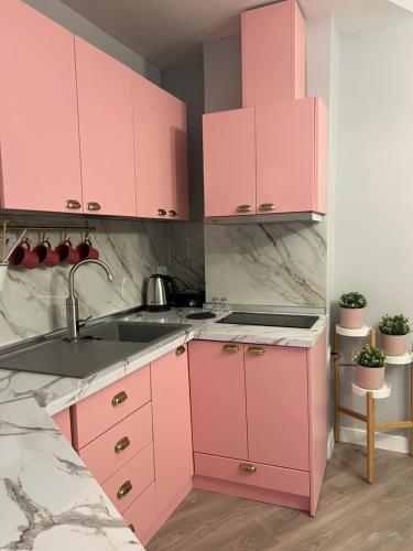 a pink kitchen with pink cabinets and a sink at Central Gem Tirana in Tirana